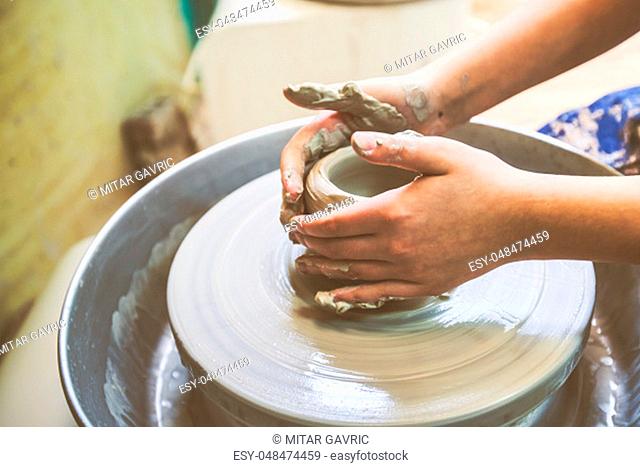 Child hands shaping clay on pottery wheel at workshop