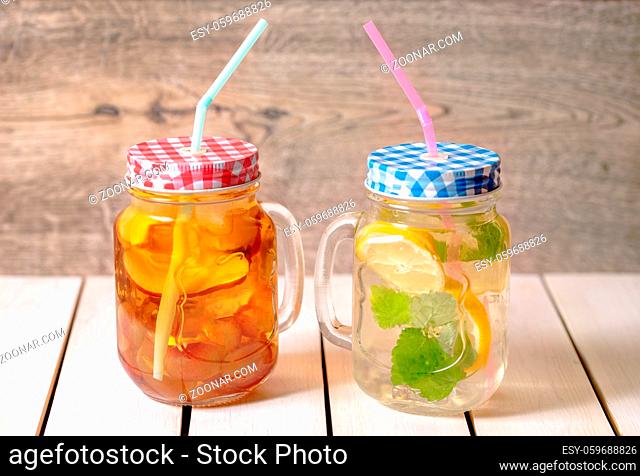 Lemon, mint, apple and grape detox water in a mason jar glass with straw and slices against a rustic wooden background