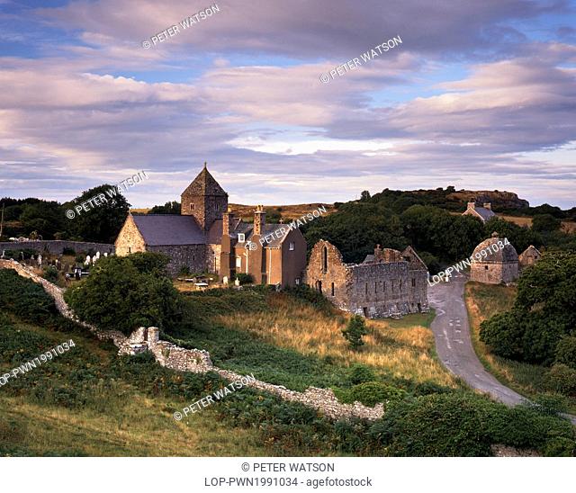 Wales, Anglesey, Beaumaris. Fading sunlight illuminates the remains on Penmon Priory and Priory church which serves as the parish church today