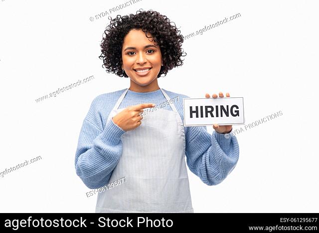 smiling woman in apron holding hiring sign