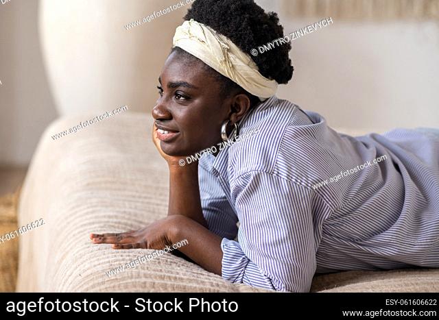 Day-dreaming. African american woman laying on bed and looking dreamy