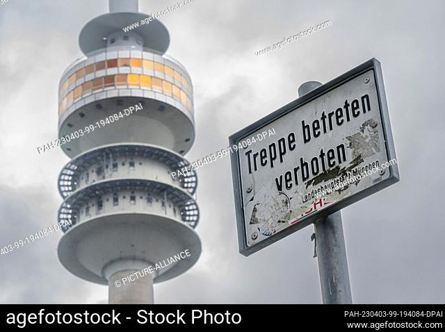 03 April 2023, Bavaria, Munich: A sign with the inscription ""Treppe betreten verboten"" (Do not enter stairs) stands in front of the backdrop of the TV tower...