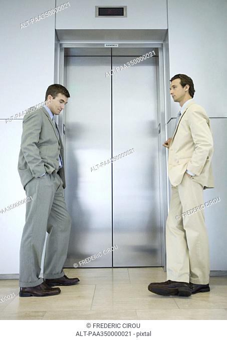 Two businessmen waiting by elevator door