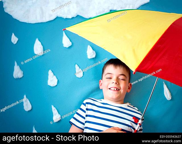 Little boy on blue background in coat with drop shapes and cloud