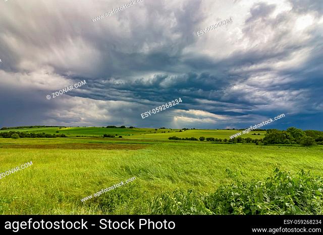 scenic view of stormy clouds over the green field