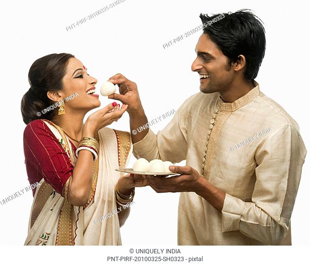 Bengali man feeding a rasgulla to his wife