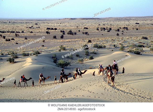 INDIA, RAJASTHAN, GREAT INDIAN (THAR) DESERT, NEAR JAISALMER, SAND DUNES IN EVENING LIGHT, TOURISTS ON CAMELS