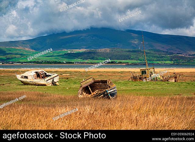 Boats in the grass, with clouds over the Lake District National Park in the background, seen in Askam-in-Furness, Cumbria, England, UK