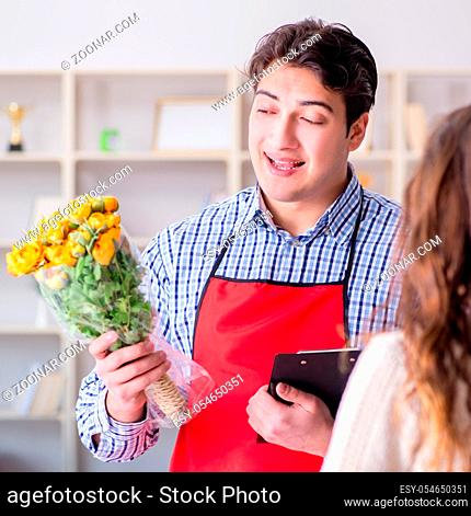 The flower shop assistant selling flowers to female customer