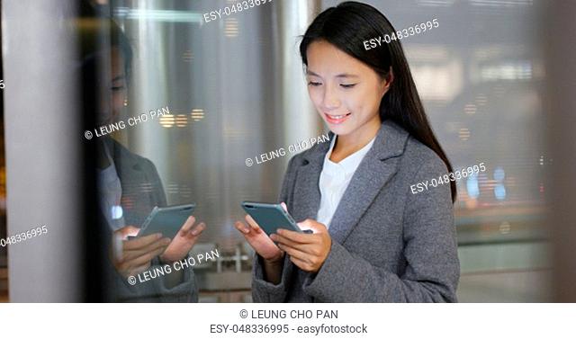 Business woman use of smart phone in city with window reflection