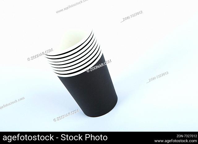Close up front view of recycled black paper glasses on end, isolated on white background