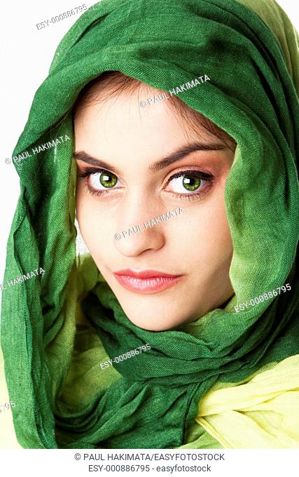 Portrait of mysterious beautiful Caucasian Hispanic Latina woman face with green penetrating eyes and green fashion scarf wrapped around head, isolated