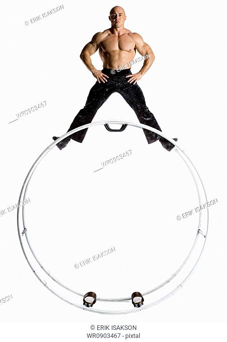 Male bodybuilder posing on top of German wheel