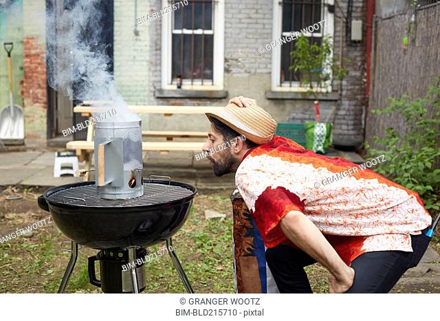 Caucasian man lighting charcoal for grill in backyard