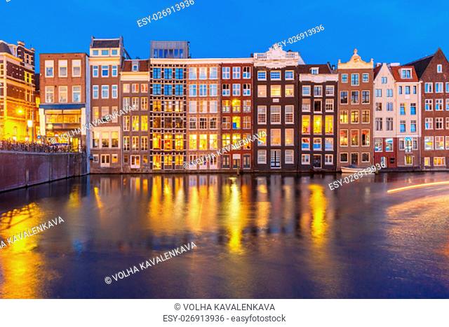 Beautiful typical Dutch dancing houses at the Amsterdam canal Damrak at night, Holland, Netherlands