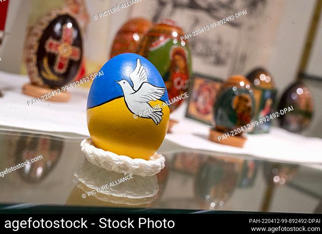 12 April 2022, Baden-Wuerttemberg, Sonnenbühl: An Easter egg painted in the colors of the Ukrainian national flag and a dove of peace is seen in a display case...