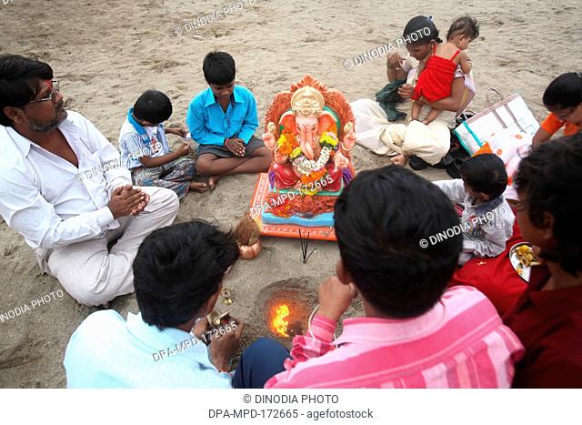 Family worshipping of lord ganesh before immersion at mahim ; Bombay Mumbai ; Maharashtra ; India NOMR