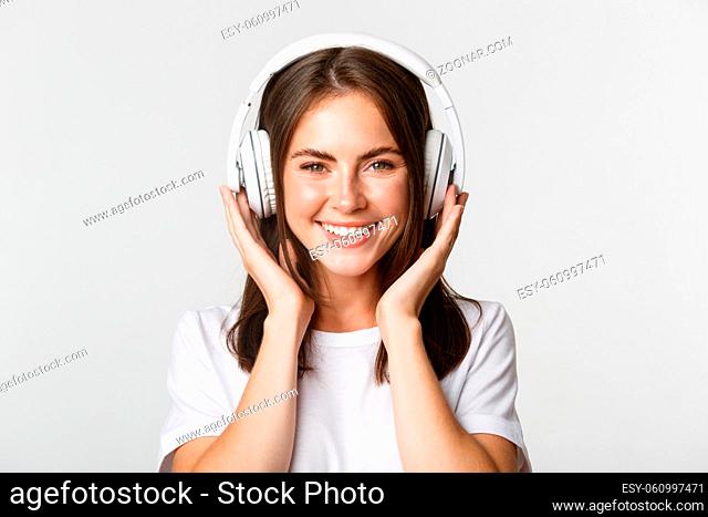 Close-up of beautiful happy girl smiling, enjoying listening music in wireless headphones