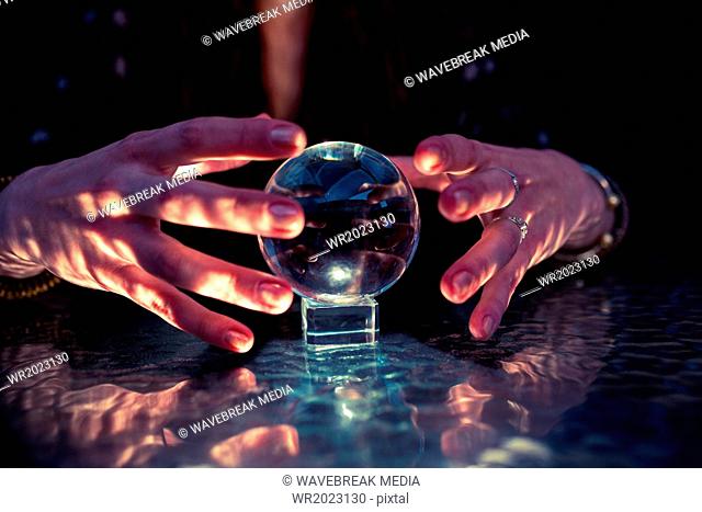 Mid section of fortune teller woman using crystal ball