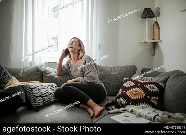 Woman cheerfully telephoned on the couch