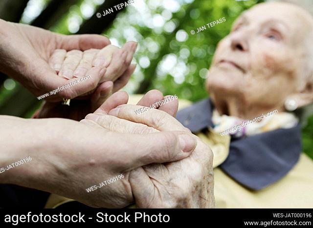 Germany, North Rhine Westphalia, Cologne, Senior woman holding hands of mature woman, close up