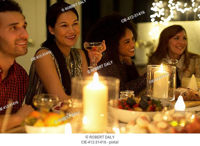 Smiling friends drinking champagne at candlelight Christmas dinner