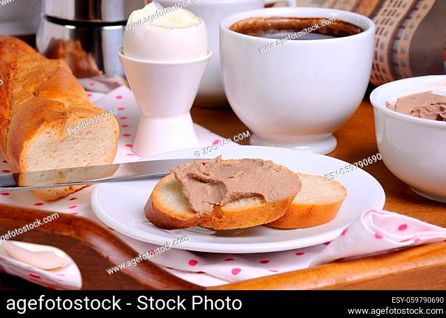 A slice of toast spread with liver pate for breakfast and a cup of coffee on a tray