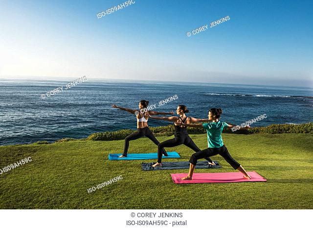 Women on cliff, in yoga positions