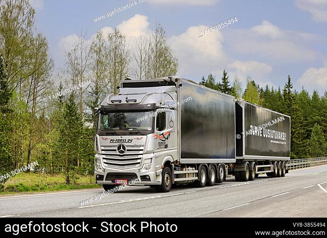 Silver Mercedes-Benz Actros truck of PE-Forss Oy pulls peat transport trailer on highway 2 on day of spring. Forssa, Finland. May 14, 2021