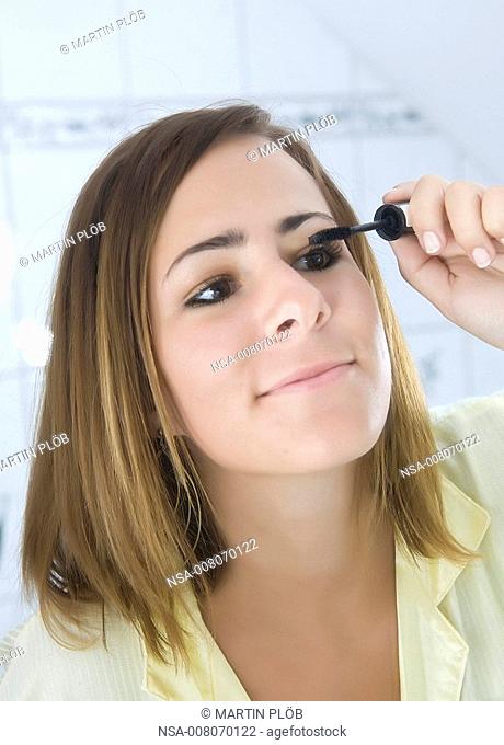 girl doing her make-up, applying mascara