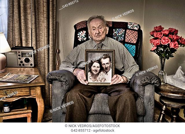 Harry, 103 years old, holds portrait of himself and wife when they were young