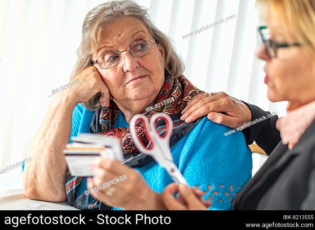 Financial consultant handing scissors to senior lady holding credit cards