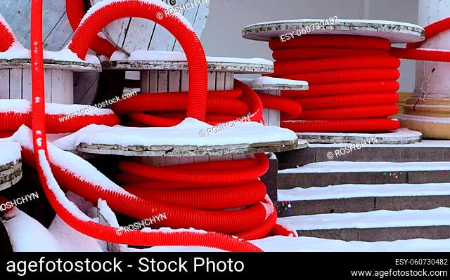 Large coils of red flexible corrugated pipe used to protect cables in electrical installations. Lots of colored polyethylene plastic hose used in construction...