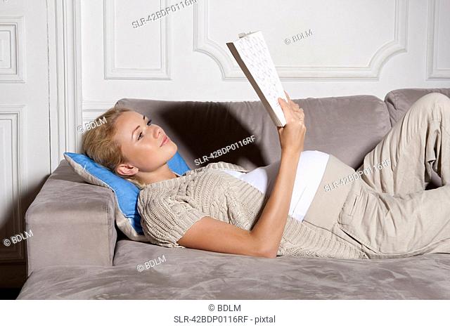 Pregnant woman reading on sofa