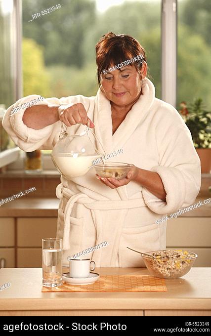 Woman at breakfast, prepares muesli, breakfast, having breakfast, pot of milk, bowls, muesli, cup of coffee, glass of water, having breakfast, prepare, pour