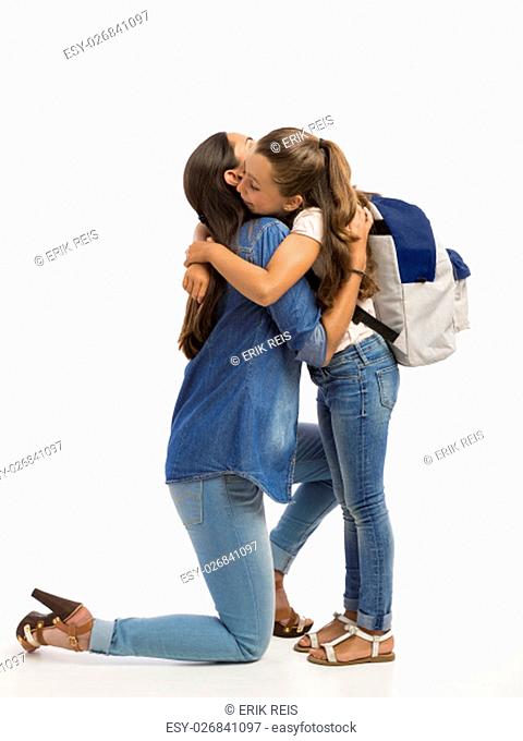 Mother hugging her little daughter and saying good-bye on the first day of school