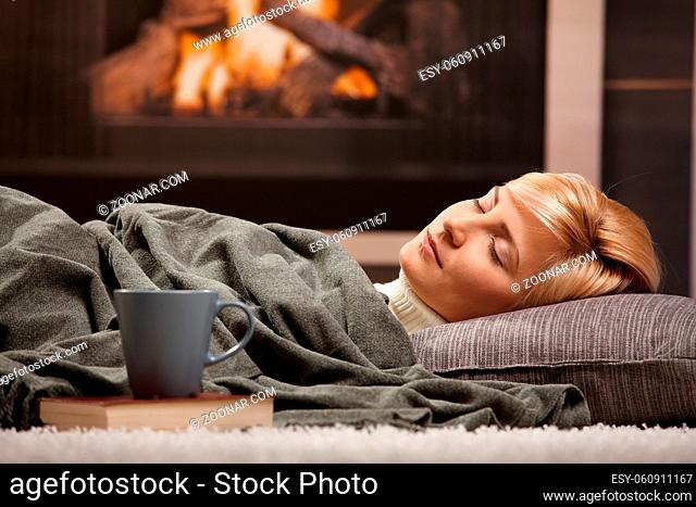 Woman sleeping at home lying on floor in front of a fire place