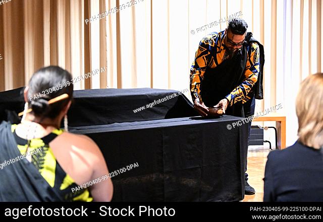 05 April 2023, Baden-Württemberg, Stuttgart: Mana Caceres from Hawaii holds a bowl of water to covered remains during a ceremonial return of human remains from...