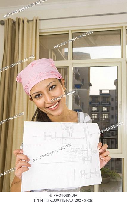 Portrait of a woman showing a blueprint and smiling