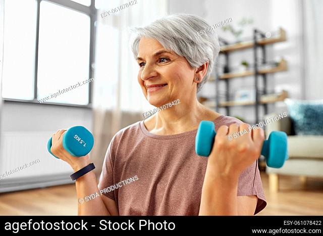 senior woman with dumbbells exercising at home