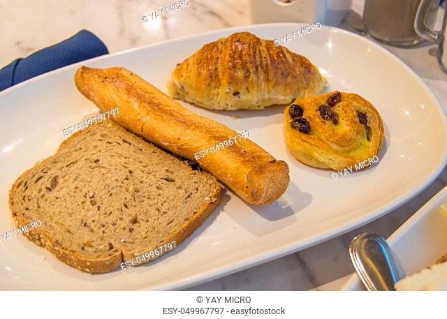 White plate with fresh pastries for Breakfast-fragrant bread, croissant, rolls