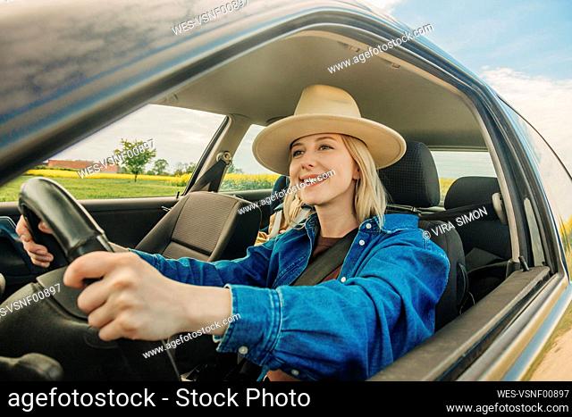 Happy woman driving car seen through window