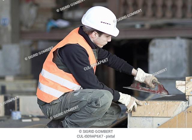 Factory worker using finishing trowel on concrete in concrete reinforcement factory