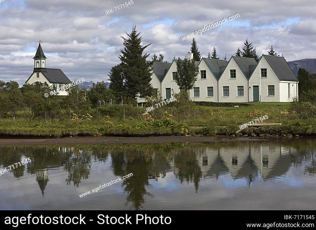 Church and five-gabled farmhouse of Þingvellir or Thingvellir, Thingvallakirkja and Thingvallabaer, reflection in the river Oxara, Golden Circle, Suðurland