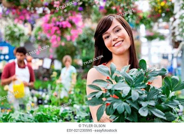 Attractive female customer holding potted plant