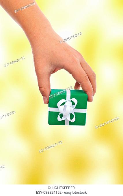 Child hand offering a gift - with copy space, on warm yellow background