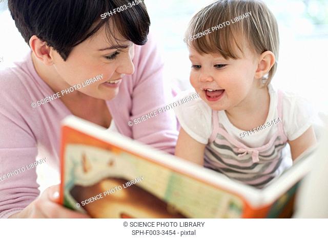 Mother and daughter. Mother reading to her 15 month old daughter