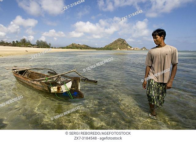 A fisherman next to his boat on the shore of Kuta beach, a fishing village south of Lombok Indonesia