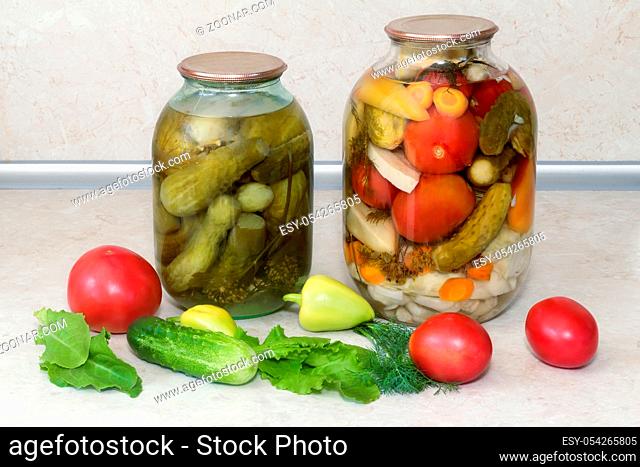 Home canning: large glass cylinders with a variety of vegetables: cabbage , tomatoes, cucumbers, peppers. Sealed with metal caps