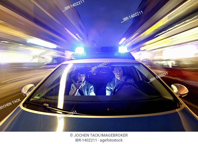 Police patrol car driving with flashing lights and sirens, Germany, Europe